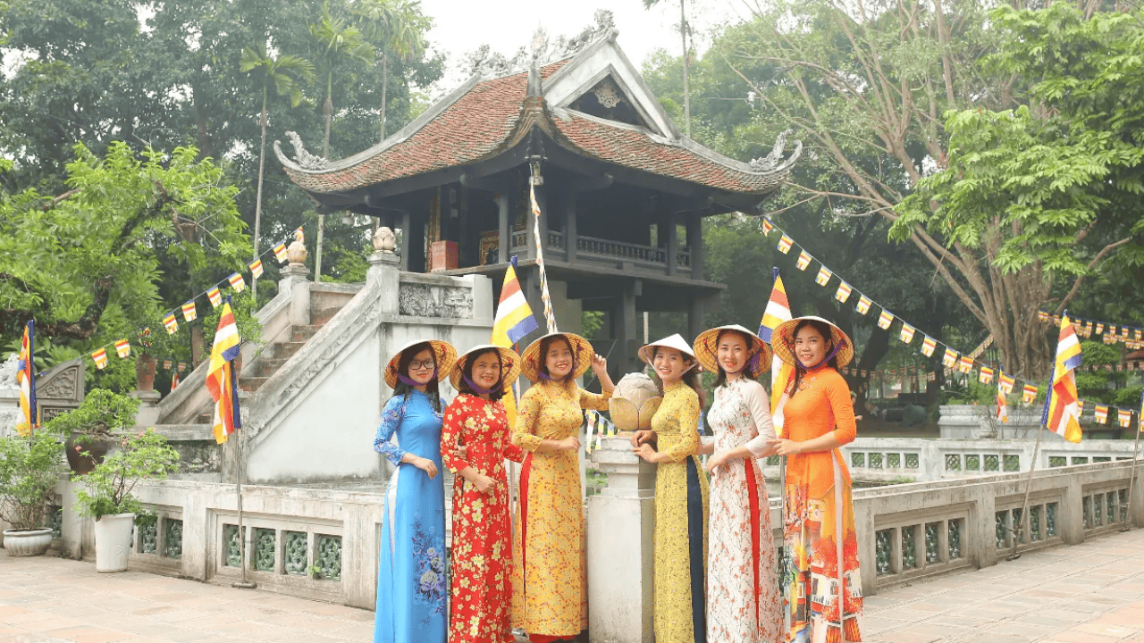 women wearing conical hats and ao dais in front of a temple