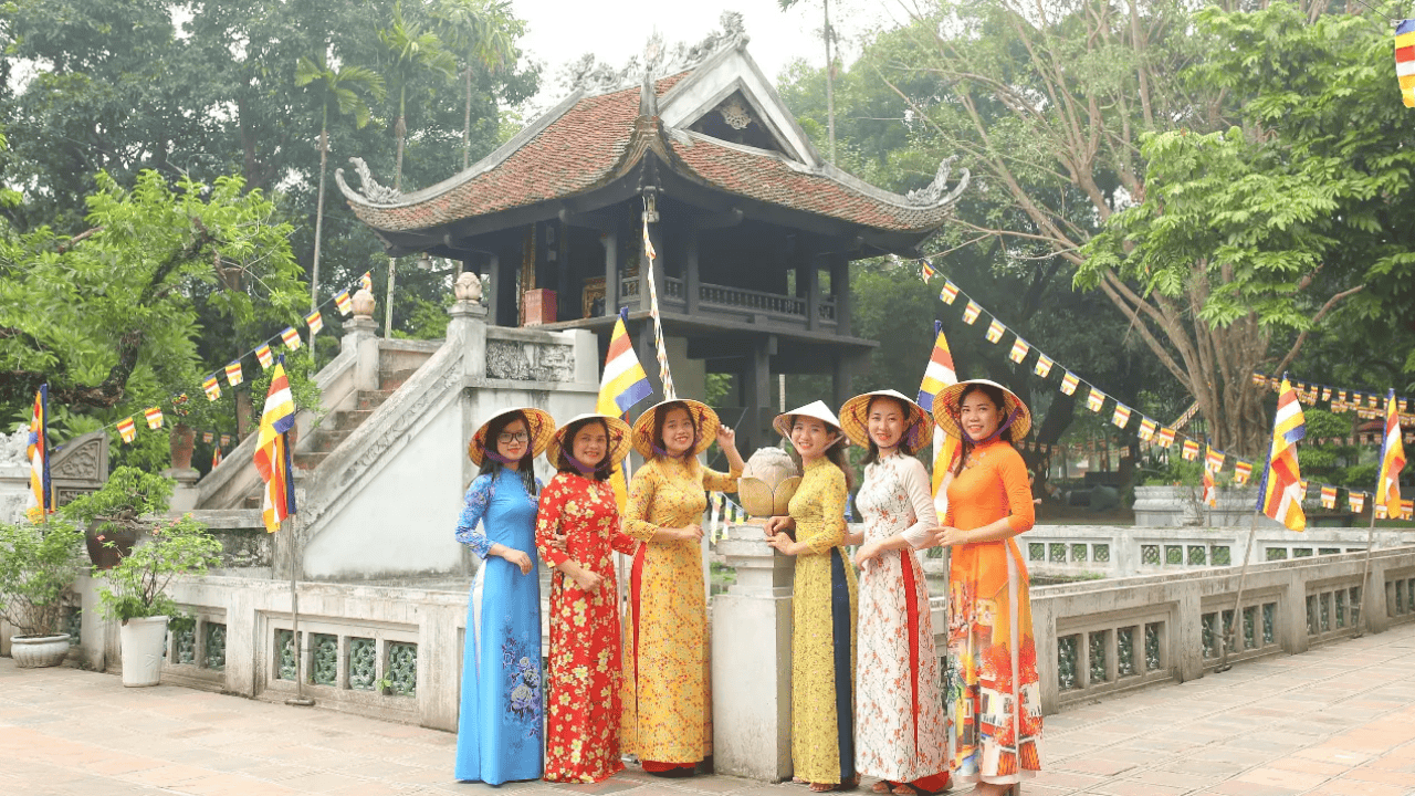 women wearing conical hats and ao dais in front of a temple